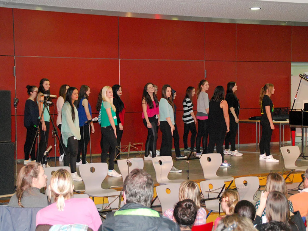 Chorgruppe singt vor der roten Wand.